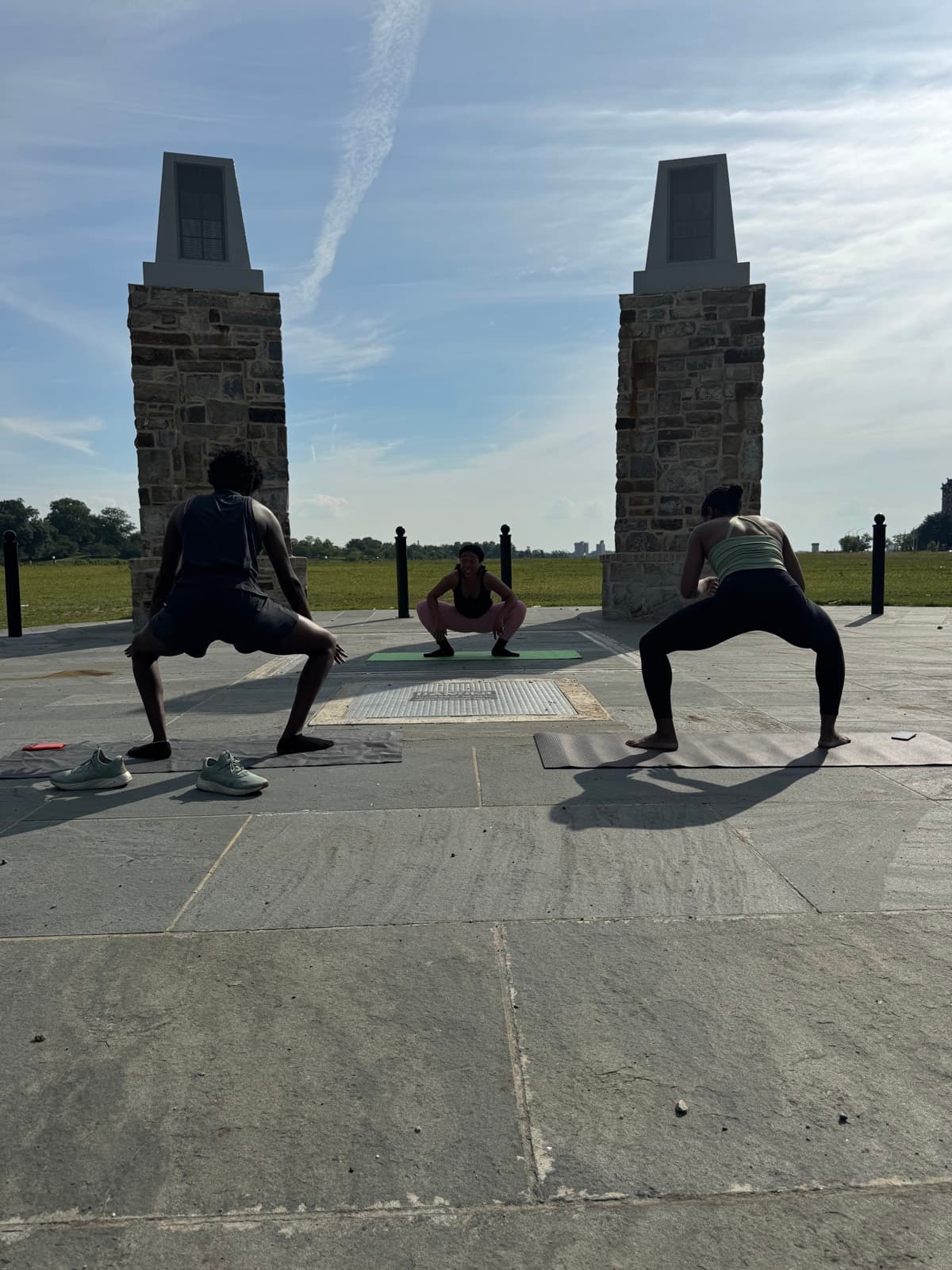 FitCamp class holding deep squats in front of the park monument